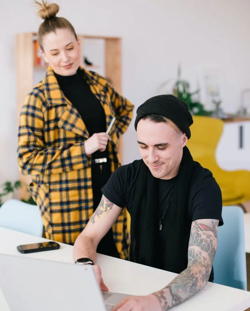Frau schaut zu, während Mann an einem Laptop arbeitet